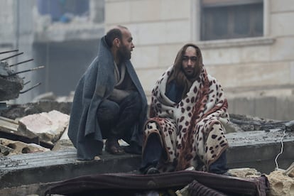 Men rest on the rubble, following an earthquake, in rebel-held town of Jandaris, Syria.