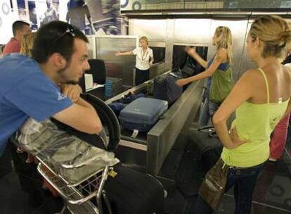 Varios pasajeros esperan el pasado miércoles a que funcionen las cintas transportadoras del aeropuerto de El Prat para facturar sus equipajes.