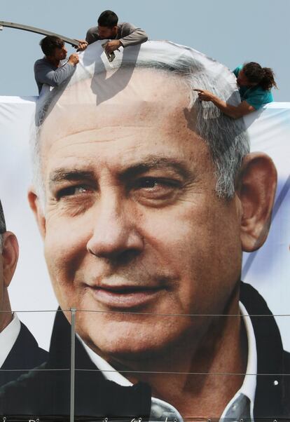 Unos trabajadores cuelgan una pancarta electoral del primer ministro israelí Benjamin Netanyahu, en Jerusalén.