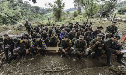 TO GO WITH AFP STORY by Hector Velasco
Revolutionary Armed Forces of Colombia (FARC) guerrillas listen during a "class" on the peace process between the Colombian government and their force, at a camp in the Colombian mountains on February 18, 2016. They still wear green combat fatigues and carry rifles and machetes, but now FARC rebel troops are sitting down in the jungle to receive "classes" on how life will be when they lay down their arms, if their leaders sign a peace deal in March as hoped.  AFP PHOTO / LUIS ACOSTA