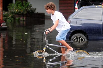 Un niño circula con su bicicleta en una calle inundada en La Plata (Argentina).