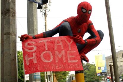 Un voluntario disfrazado de Spider-Man muestra un cartel con el lema: