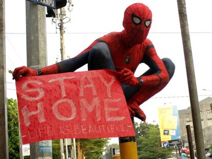 Un voluntario disfrazado de Spider-Man muestra un cartel con el lema: