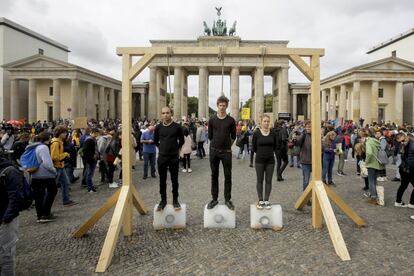 Tres personas subidas en bloques de hielo debajo de la horca protestan contra la ausencia de políticas climáticas en la Puerta de Brandenburgo en Berlín (Alemania), el día 20 de septiembre.