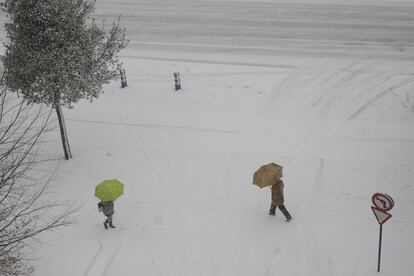 Dos personas pasean por la calle Obispo Ballester de Vitoria cubierta por la nieve.