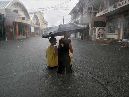 Dos jóvenes vadean una calle inundada en la ciudad portuaria de La Ceiba (Honduras).
