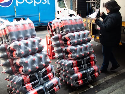 Una mujer recibe botellas de refresco en su negocio en Ciudad de México, el 27 de diciembre de 2022.