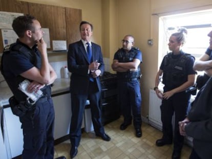 El premier brit&aacute;nico, David Cameron, y su ministra de Interior, Theresa May, hablan en Slough con funcionarios de inmigraci&oacute;n. 