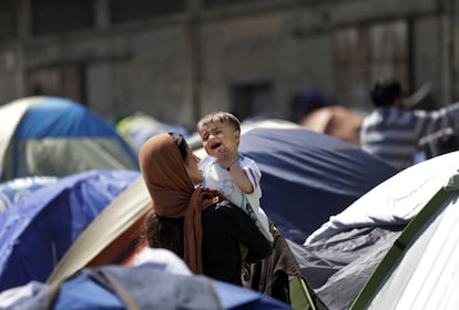 Uma imigrante segurando um bebê na quarta, no porto de Pireu.