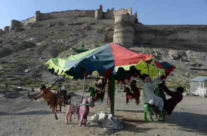 Niños afganos se divierten en un tiovivo destartalado, en la ciudad de Kabul.