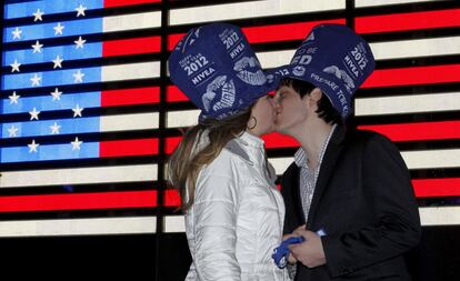 Una pareja se besa delante de un luminoso con la bandera de EE UU en la plaza de Times Square, Nueva York.
