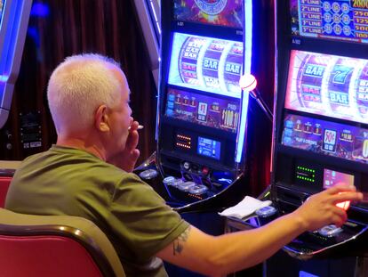 A gambler smokes while playing a slot machine at the Hard Rock casino in Atlantic City N.J. on Aug. 8, 2022.