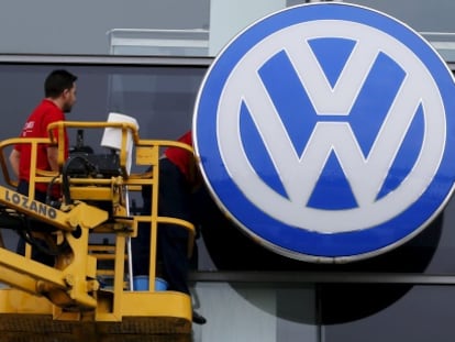 Obreros limpian la fachada del concesionario de Volkswagen en Sevilla.