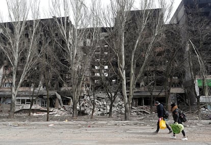 Dos personas caminan frente a un edificio de apartamentos destruido en Mariupol, en el sudeste de Ucrania. Este viernes, la Cruz Roja ha anunciado que la operación de evacuación de civiles de la ciudad portuaria, asediada desde hace más de un mes, ha fracasado debido a que era imposible acceder a la localidad.