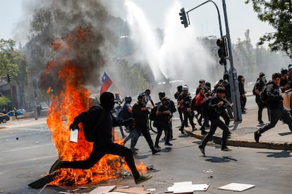 Manifestantes corren de los cañones de agua que dispara la policía, este martes, en Santiago.