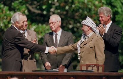 El ministro de Exteriores de Israel Simon Peres (i) saluda al presidente de la Organización para la Liberación de Palestina, Yasir Arafat (d), junto al primer ministro de Israel Isaac Rabin (c), el presidente de EE UU Bill Clinton (d) y el ministro de Exteriores ruso, Andrei Kozyrev (2º izq), durante la firma del acuerdo de paz para Oriente Medio de Washington, en 1993.