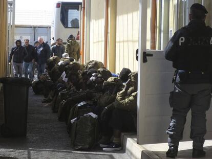 Inmigrantes vigilados por agentes esperan a que varios autobuses los trasladen desde el &#039;hotspot&#039; de Pozzallo (Sicilia) a otros centros de acogida en Italia.
