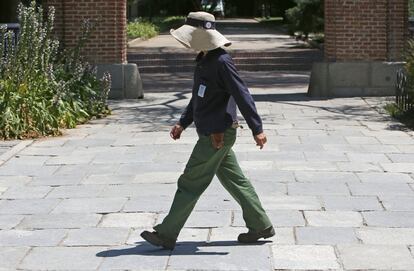 Un empleado de mantenimiento del Parque de El Retiro camina protegido bajo el sol.