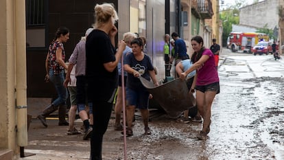 Varios vecinos trabajan en achicar agua y barro, este domingo en Santa Barbara, Tarragona.