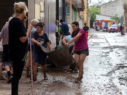 Varios vecinos trabajan en achicar agua y barro, este domingo en Santa Barbara, Tarragona.