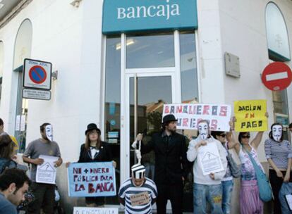 El hombre desahuciado (con traje de presidiario) y un grupo de indignados protestan ante el banco.