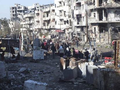 Un grupo de civiles caminan entre las ruinas de la ciudad con sus pertenencias hacia un punto de encuentro para ser evacuados de una zona sitiada de Homs el 9 de febrero de 2014.