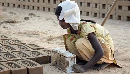 Una niña fabrica ladrillos en una población en India. 