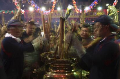 Varias personas colocan varillas de incienso en el tempo de Guan Yin, Singapur. La víspera del inicio del Nuevo Año Lunar los fieles se reúnen para ofrecer incienso en busca de suerte y prosperidad.