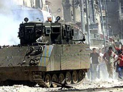 Jóvenes palestinos lanzan piedras contra un tanque israelí en un campo de refugiados de Cisjordania.