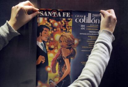Una joven coloca un cartel que anuncia un cotillón de Nochevieja en un bar de Vitoria.