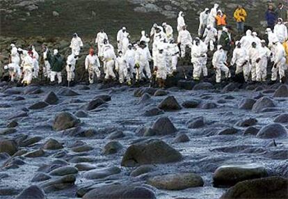 Un grupo de voluntarios trabaja contra una enorme mancha de fuel en el cabo de Touriñán, en A Coruña.