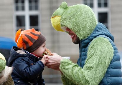 Un niño comparte una hamburguesa con su padre durante el carnaval de Düsseldorf (Alemania), el 26 de febrero de 2017.