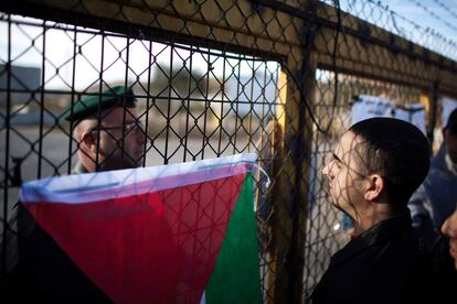 Un palestino habla con un policía de frontera israelí en el paso de Ramala, durante la espera de la llegada de prisioneros palestinos liberados por Israel.