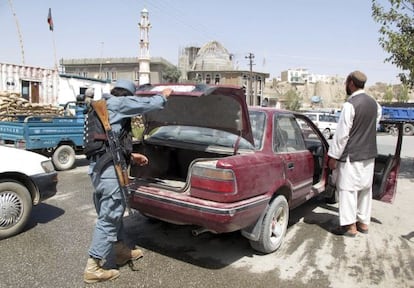 Policías afganos registran un vehículo en un puesto de control después del atentado suicida de Wardak.