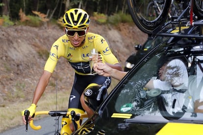 El colombiano Egan Bernal, del Equipo Ineos, bebe champán junto al coche de su director del equipo.