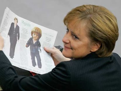 Angela Merkel sostiene un periódico en el que se muestra a una muñeca inspirada en la futura canciller.