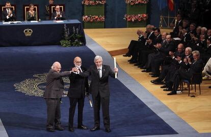 os físicos Peter Higgs (i) y François Englert (c), y el presidente del Laboratorio Europeo de Física de Partículas (CERN), Rolf Heuer (d), se estrechan las manos frente al público tras recibir de don Felipe el Premio Príncipe de Asturias 2013 a la Investigación Científica y Técnica, durante la ceremonia de entrega de estos galardones, en un acto celebrado en el Teatro Campoamor de Oviedo.