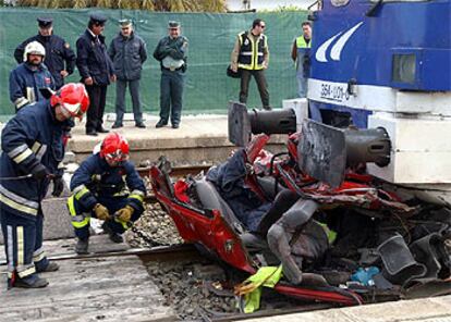 Los bomberos tratan de separar del tren los restos del vehículo siniestrado.