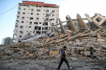La escalada desatada tras el disparo de proyectiles sobre Jerusalén el lunes entró en la madrugada del miércoles en una dinámica de guerra generalizada con bombardeos masivos del Ejército israelí, el derribo de edificios de varias alturas con los misiles de la aviación, y asesinatos selectivos de jefes de las milicias islámicas de Hamás y la Yihad Islámica. En la imagen, un palestino pasa delante de los restos de una torre destruida por los ataques aéreos israelíes, en Gaza, este miércoles.