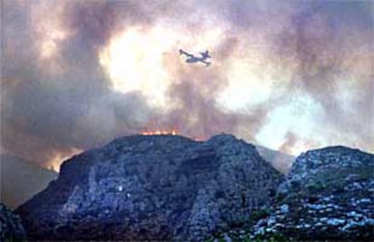 Un avión de los medios de extinción intentaba ayer apagar las llamas en una montaña de La Vall de la Gallinera.