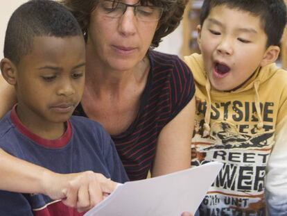 Una maestra y dos ni&ntilde;os inmigrantes en un aula de clase de catal&aacute;n. 