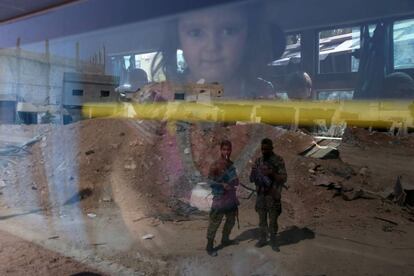 Tropas del gobierno sirio se reflejan en la ventana de un autobús que evacua los habitantes de la ciudad siria de Daraya.