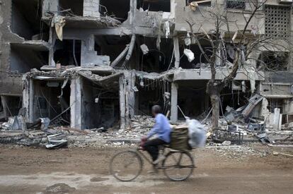 Un hombre pasa ante edificios destruidos en un suburbio de Damasco.
