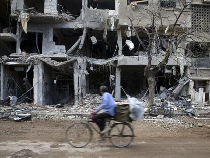 Um homem passa diante de edifícios destruídos em um subúrbio de Damasco.