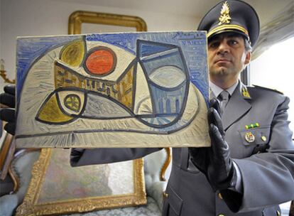 Un Policía muestra una de las obras de arte escondidas en la casa del fundador de Parmalat