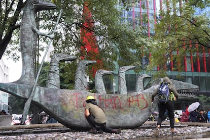 Asistentes a la protesta realizan pintas que aluden a la desaparición de los 43 estudiantes sobre esculturas expuestas en Paseo de la Reforma, en Ciudad de México.