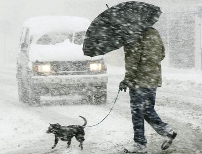 Un vecino de la localidad de Matamorosa, Cantabria, cruza una calle en medio de una fuerte nevada.