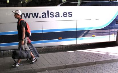 Un joven con maletas junto a un autobús de la empresa Alsa en la Estación Sur de Madrid.