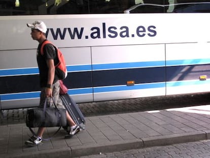 Un joven con maletas junto a un autobús de la empresa Alsa en la Estación Sur de Madrid.