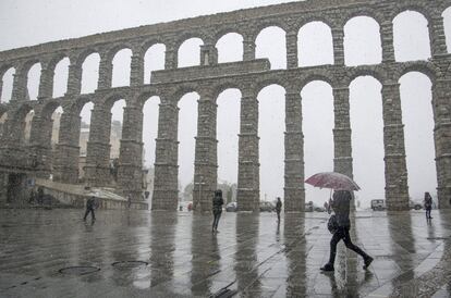 Varias personas pasean bajo la nieve junto al acueducto de Segovia, el 3 de marzo de 2017. Todas las provincias de Castilla y León salvo Valladolid están en alerta amarilla.